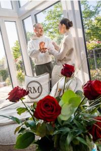 a man and a woman standing in a room with roses at Das Oswald's Boutique Hotel in Cuxhaven