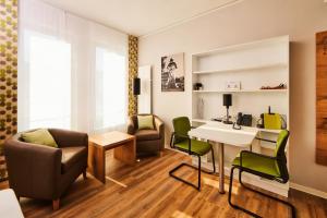 a living room with a table and chairs and a desk at ADAPT APARTMENT HOTEL Siegen in Siegen