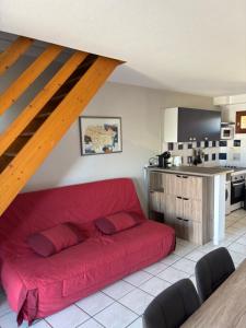 a red couch in a living room with a kitchen at La mer en liberté in Gruissan