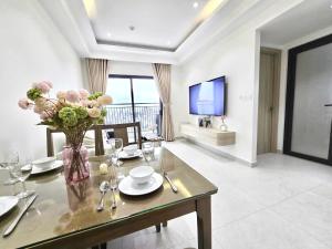 a dining room with a table with a vase of flowers at Lloyd's Daily Suites - SOHO Residence, Bui Vien Walking Street, BenThanh Market & SG's Vibe in Ho Chi Minh City
