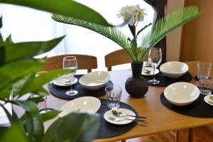 a wooden table with plates and wine glasses on it at カラハーイもとぶ 碧 in Motobu