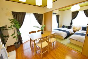 a bedroom with a table and a bed and a table and chairs at カラハーイもとぶ 碧 in Motobu