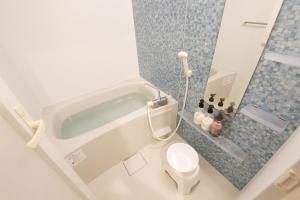 a bathroom with a bath tub and a toilet at カラハーイもとぶ 碧 in Motobu