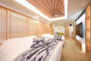 two beds in a hotel room with a tv at HOTELみなと-Minato- 新宿 in Tokyo