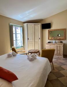 a bedroom with a large white bed and chairs at Colomba Hôtel Centre-Ville Historique in Bonifacio