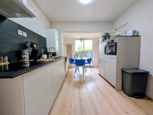 a kitchen with white cabinets and a table with blue chairs at Ma Casa in Boulogne-sur-Mer