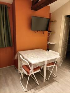a white table and chairs with a tv on a wall at Maisonnette étape équestre in Nogent-lʼArtaud