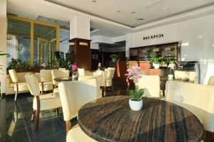 a restaurant with white chairs and tables and a table with flowers at Willa Wodnik in Świnoujście