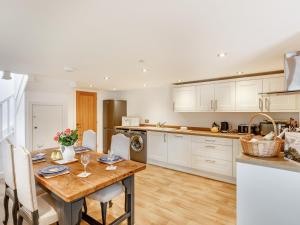 a kitchen with white cabinets and a wooden table at The Granary - Uk38980 in Llandyssil