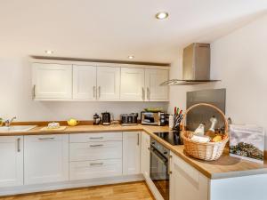 a kitchen with white cabinets and a basket on the counter at The Granary - Uk38980 in Llandyssil