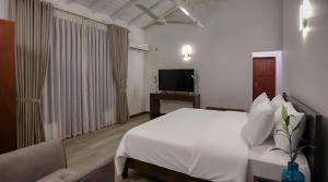 a bedroom with a white bed and a television at Villa Barracuda in Sri Jayewardenepura Kotte