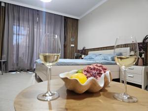 two glasses of wine and a bowl of fruit on a table at Blue Marina Sunset in Sozopol