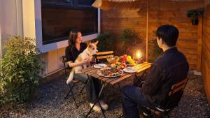 a woman and a man sitting at a table with a dog at gyeongju planb pet pension in Gyeongju +1 photo