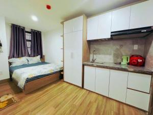 a bedroom with a bed and a kitchen with white cabinets at Thien Khanh Hotel for rent in Danang +9 photos
