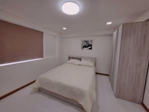a white bedroom with a bed and a window at Hugg daily airport 1 in Samutprakarn