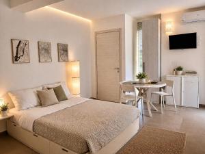 a white bedroom with a bed and a table at 18 Gradi Apartments in Birgi Vecchi