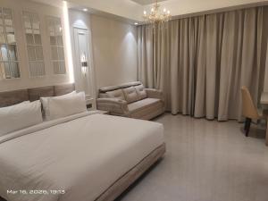 a bedroom with a large white bed and a chair at Shagun Hotel & Resorts in Khandwa