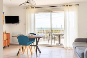 a living room with a table and a large window at "La Sorra" Résidence en Bord de mer in Saint-Cyprien