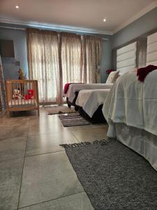 a bedroom with two beds and a crib at Elitha Boutique Bed and Breakfast in Mogwase