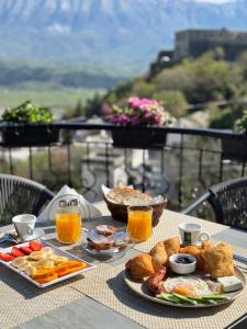 a table topped with plates of food and orange juice at Castle Hotel in Gjirokastër