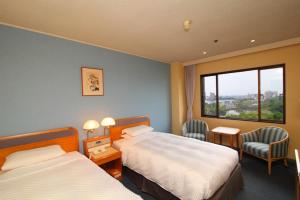 佐賀市にあるホテルニューオータニ佐賀のベッド2台と窓が備わるホテルルームです。