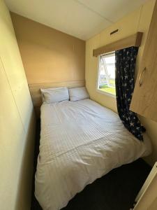 a small bed in a small room with a window at Seaside views in North Seaton