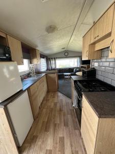 a kitchen with wooden cabinets and a stove top oven at Seaside views in North Seaton +2 photos