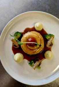 a white plate with a dish of food with broccoli at Gîte de la Cour in Campandré-Valcongrain