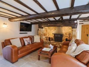 a living room with leather couches and a fireplace at Bridge Cottage in Bridport