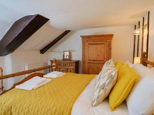 a bedroom with a bed with yellow and white pillows at Bridge Cottage in Bridport