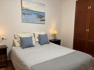 a bedroom with a bed with two blue pillows at Sanmao Vibbecanarias Playa del hombre Telde in Playa del Hombre