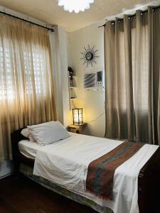 a bedroom with a bed and a window with curtains at Anton & Isabel Charming Home in Bangued in Bangued