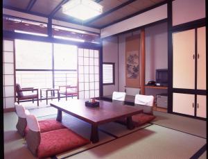 comedor con mesa, sillas y ventanas en Oyado Sansui en Achi