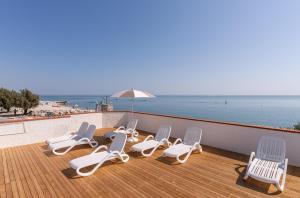 a group of lounge chairs and an umbrella on a deck at Club del Sole Roseto degli Abruzzi Easy Camping Village in Roseto degli Abruzzi