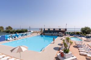 a view of the pool at a hotel with chairs and a person standing in front at Club del Sole Roseto degli Abruzzi Easy Camping Village in Roseto degli Abruzzi
