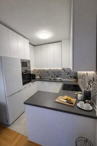 a kitchen with white cabinets and a black counter top at Zozo's Apartment in Sarajevo