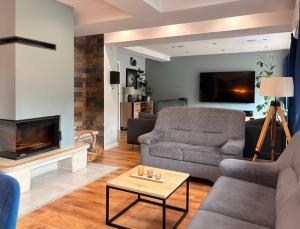 a living room with a couch and a fireplace at Breńskie Tarasy in Brenna
