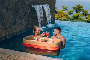 a man and woman in a pool with a boat in the water at AQUA Boutique Hotel- Secluded Ocean View Suites & Infinity Pool in Glacis