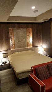 a bedroom with a large bed and a red chair at ホテルピュアゲート in Isesaki