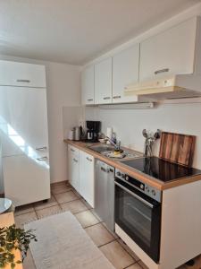 a kitchen with white cabinets and a stove top oven at Ferienwohnung Waldnest in Elmstein