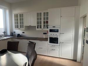 a kitchen with white cabinets and a table and chairs at Villa Le Roy in Blankenberge