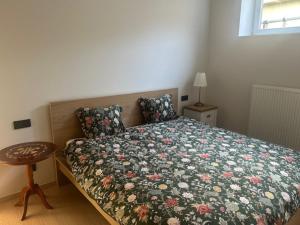 a bedroom with a bed with a floral bedspread and a table at Villa Le Roy in Blankenberge