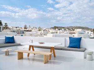 a table and bench on a balcony with white buildings at Chiara Mykonos III in Mikonos
