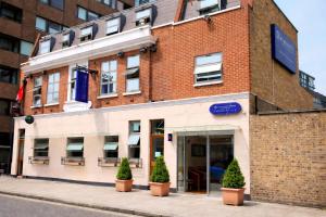 a brick building with potted trees in front of it at Eurotraveller Hotel- Express (Elephant & Castle) in London