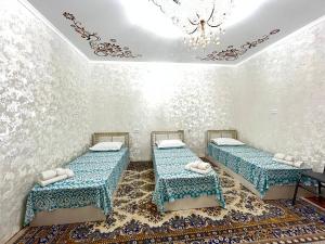 a room with two beds and a chandelier at Musobek Guest House in Khiva