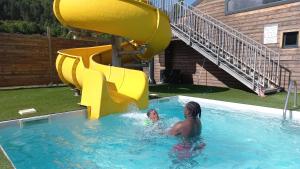 a man and a child in a pool with a slide at Refuge - Les Chalets du lac Belcaire in La Celle-sous-Gouzon