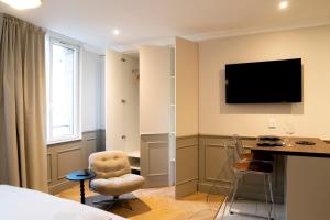a hotel room with a desk and a television on the wall at Studio haut de gamme - Hypercentre - Lit Queen in Caen