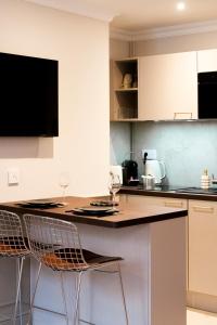 a kitchen with two chairs sitting at a counter at Studio haut de gamme - Hypercentre - Lit Queen in Caen