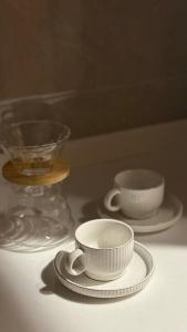 two white cups and plates sitting on a table at شقق المشرق in Jeddah