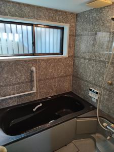 a bath tub in a bathroom with a window at 天王寺まで電車にて 約10分 福宿八尾 in Yaochō